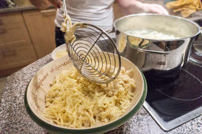 Die aufgekochten Spatzen werden aus dem heißen Wasser geschöpft und in einer Kässpatzenschüssel mit dem geriebenen Bergkäse geschichtet.