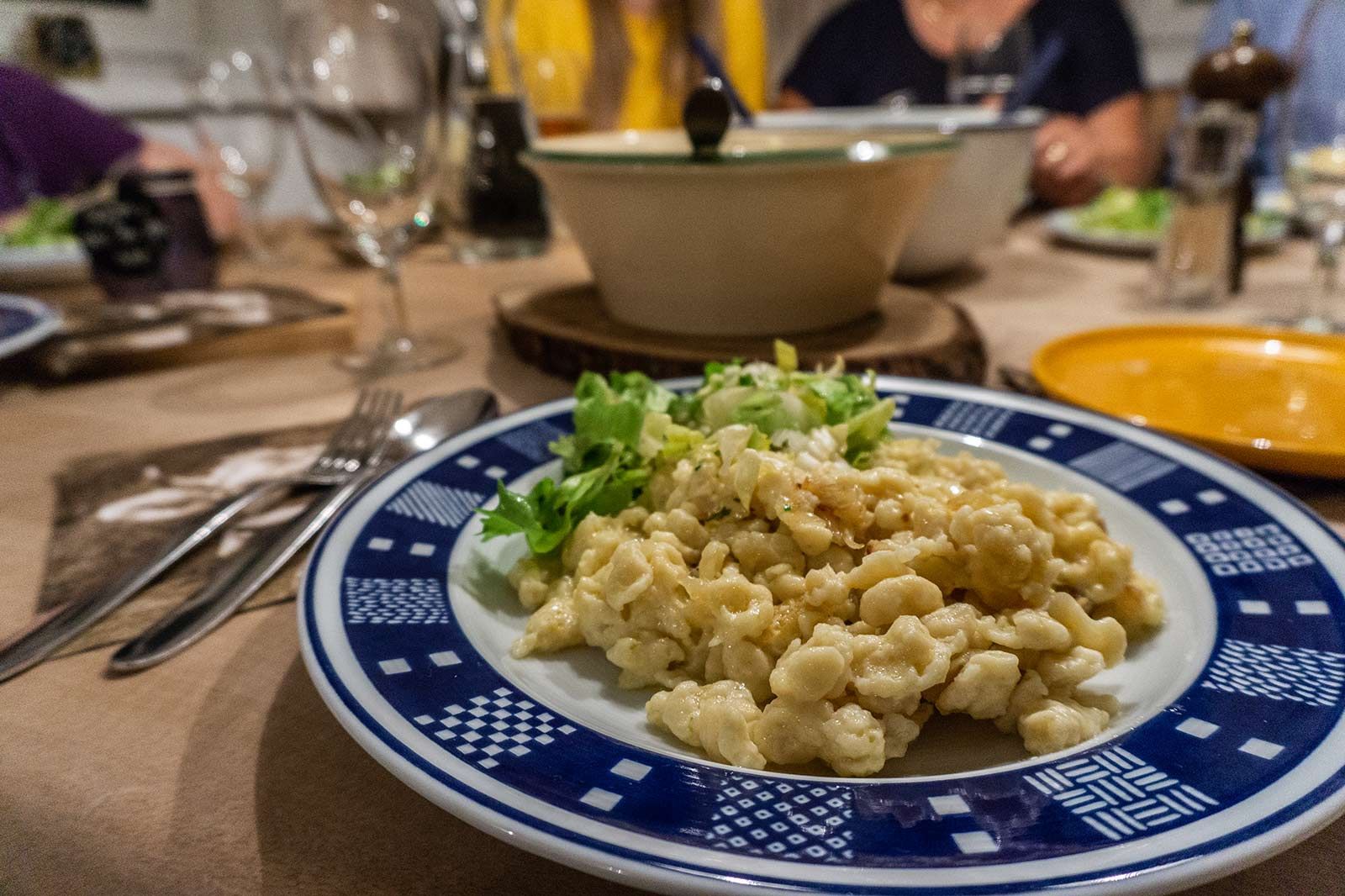 Nach der Zubereitung des Original Allgäuer Kässpatzen Rezept werden die selbstgemachten Spatzen am liebsten mit Freunden und/oder der Familie gemeinsam am Tisch gegessen. Auf den Teller gehören neben den Kässpatzen auch ein frischer Salat.